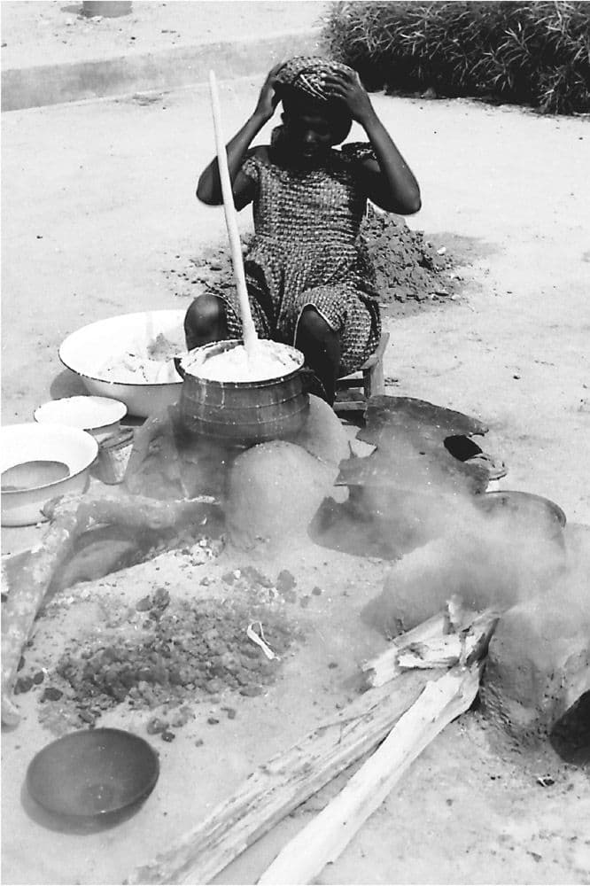 Resident creating outside kitchen stoves and mortars, Tema Community 1, photograph by Michael Hirst