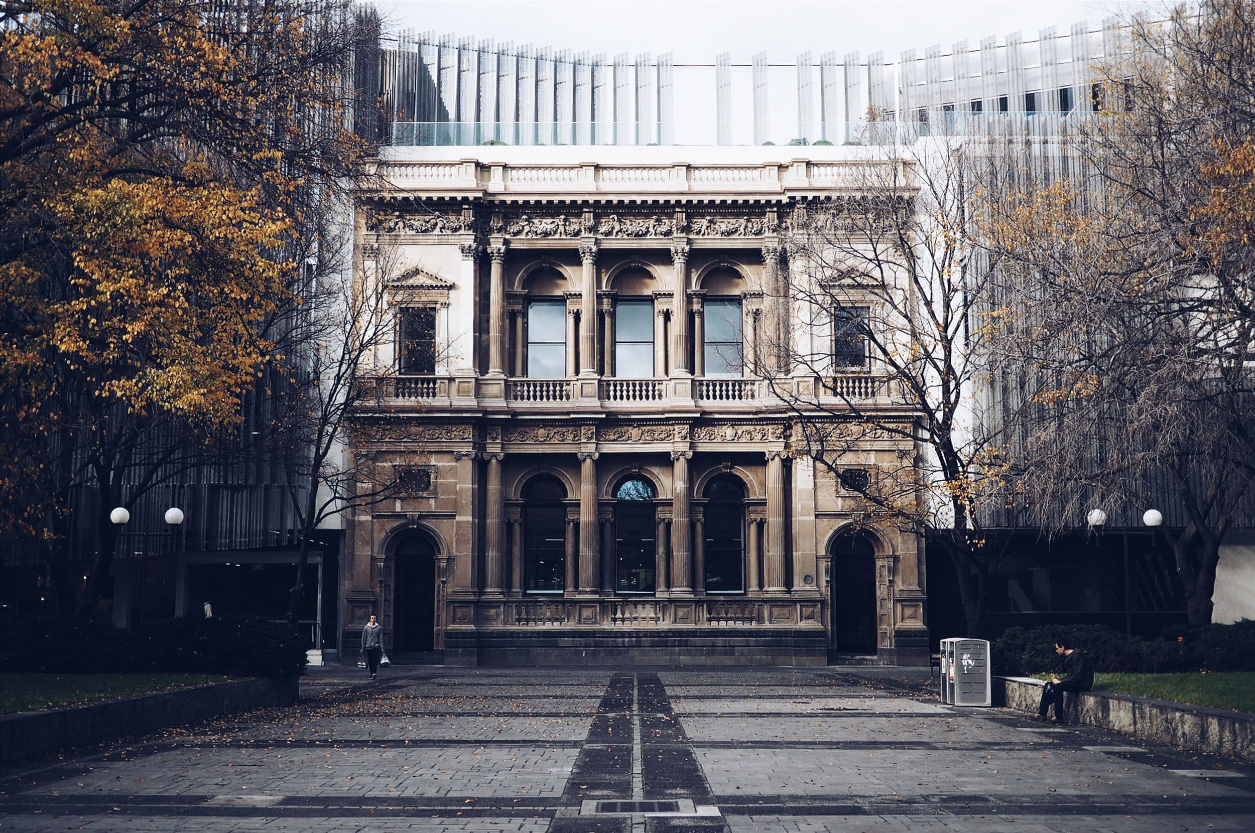 Ornate classical building with arched windows and decorative facade, surrounded by trees.