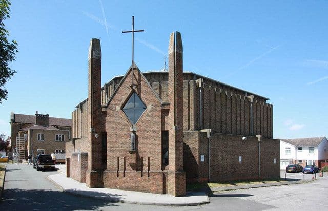 Modern brick church with a tall cross atop its facade and flanking towers.