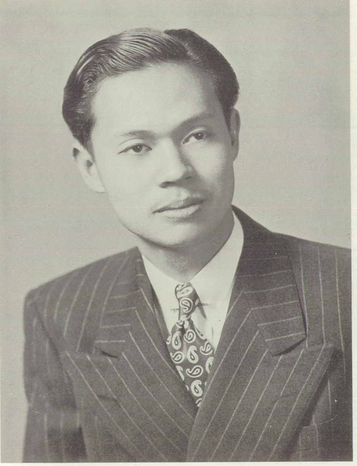 Studio portrait of a young Asian man in a pinstripe suit and patterned tie.