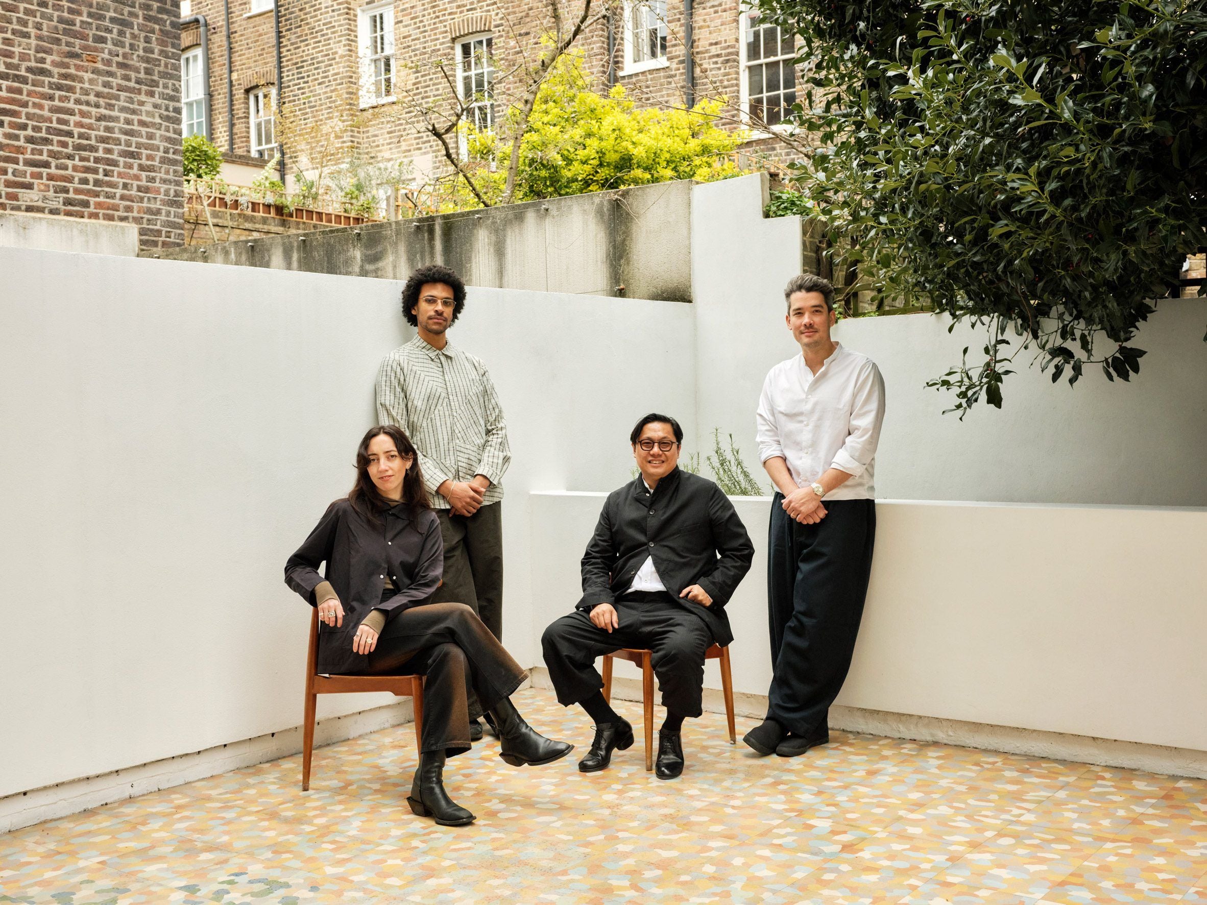 Photograph taken in a garden showing four people, two seated and two standing behind them